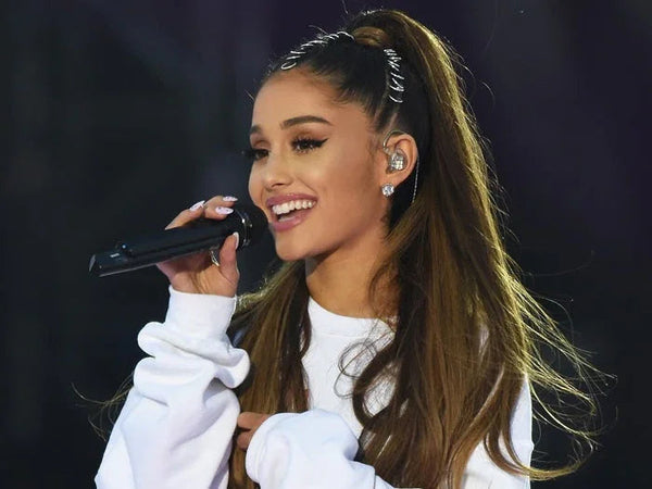 Smiling woman in white sweater singing on stage with microphone, nut-free snack bars context