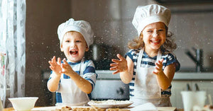 Smiling kids in chef hats and aprons baking nut-free snacks in a kitchen