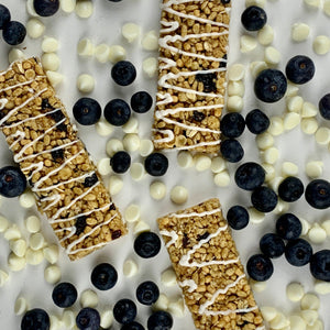 Nut-free blueberry snack bars with white drizzle, surrounded by fresh blueberries and white chips