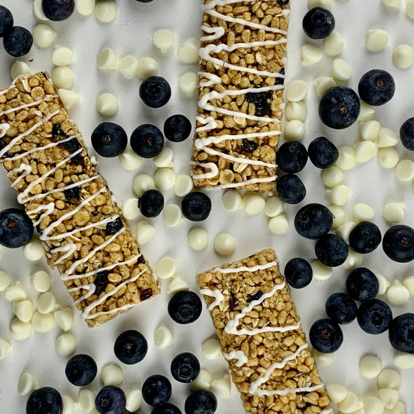 Nut-free blueberry snack bars with white drizzle, surrounded by fresh blueberries and white chips