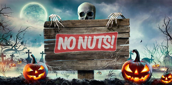 Halloween-themed No Nuts! sign held by skeleton with pumpkins, graveyard, and full moon background