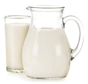 Glass and pitcher filled with milk on white background, allergy-friendly snack context