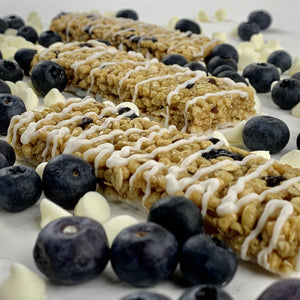 Nut-free blueberry vanilla snack bars with white drizzle, surrounded by blueberries and white chips