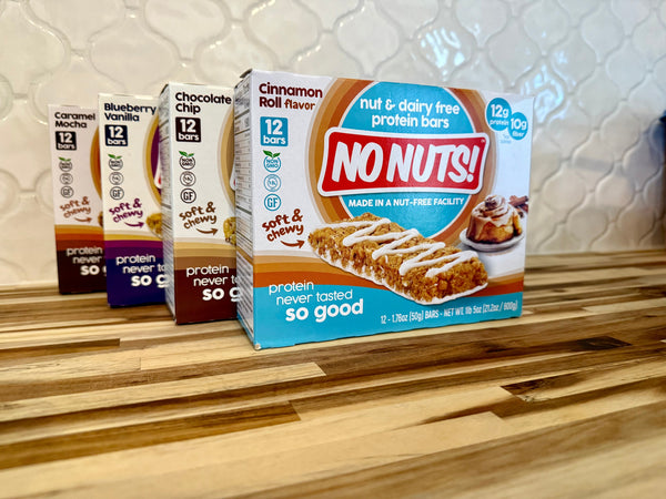 No Nuts nut-free snack bars in assorted flavors on a wood counter, allergy-friendly packaging