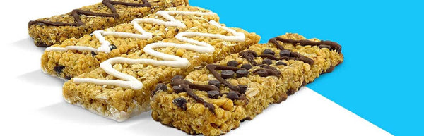 Nut-free snack bars with icing and chocolate drizzle, arranged on a blue and white background.