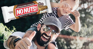 Smiling dad and son giving thumbs up outdoors, featuring No Nuts nut-free snack bar.