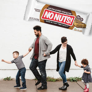 Family walking on sidewalk with No Nuts nut-free snack bar above, allergy-friendly snack
