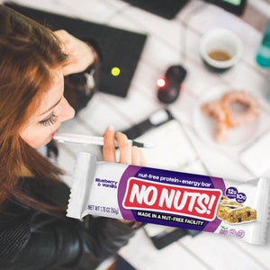 Woman planning at desk with No Nuts nut-free snack bar, coffee, and pastry