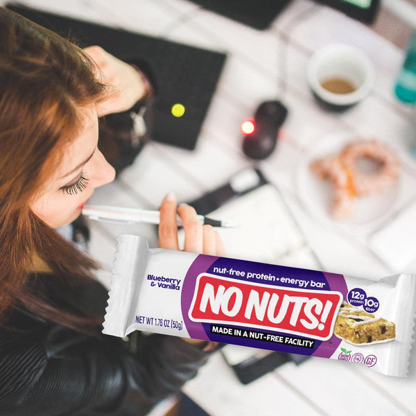Woman planning at desk with No Nuts nut-free snack bar, coffee, and pastry