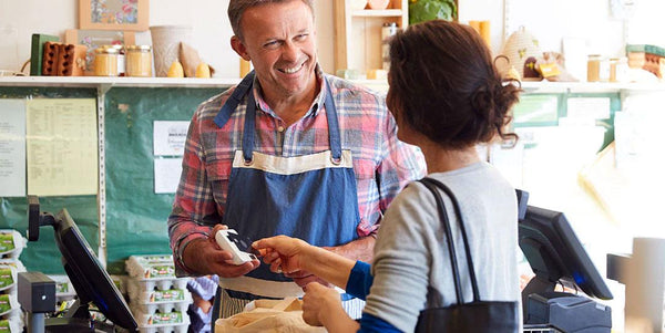 Smiling clerk helps customer at register in nut-free snack store