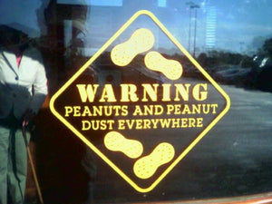 Yellow warning sign on window reads 'Warning: Peanuts and peanut dust everywhere' with peanut icons.