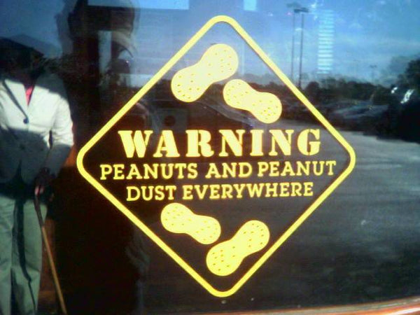 Yellow warning sign on window reads 'Warning: Peanuts and peanut dust everywhere' with peanut icons.