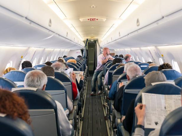 Passengers seated in a commercial airplane cabin, reading and relaxing during flight