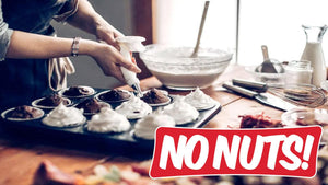 Baker icing nut-free cupcakes in a kitchen, 'No Nuts!' label in foreground.