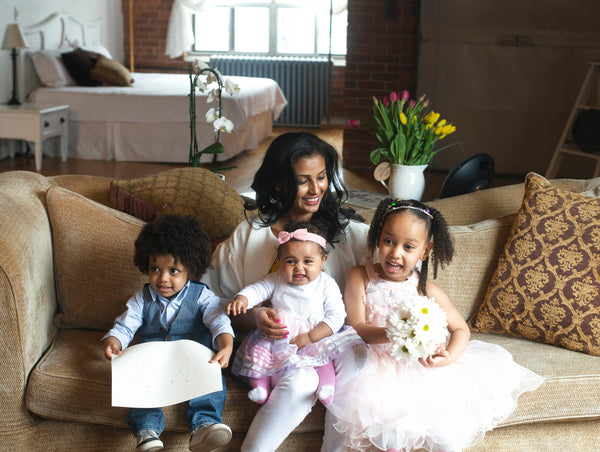 Smiling family with kids on sofa, spring flowers in background, allergy-friendly theme