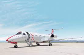 White private jet with red accents parked on a clear runway under blue sky