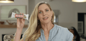 Woman holding No Nuts nut-free snack bar in kitchen, allergy-friendly school-safe snack