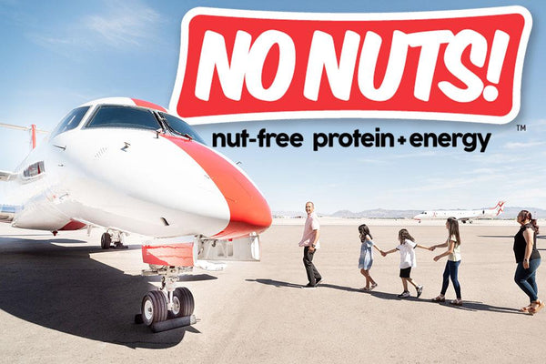 Family walks on airport tarmac by jet with No Nuts! nut-free snack bars logo above.