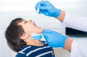 Child receives oral drops from doctor in clinical setting, relevant to nut allergy care
