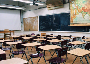 Empty classroom with student desks, chalkboard, world map, and projector, school-safe setting