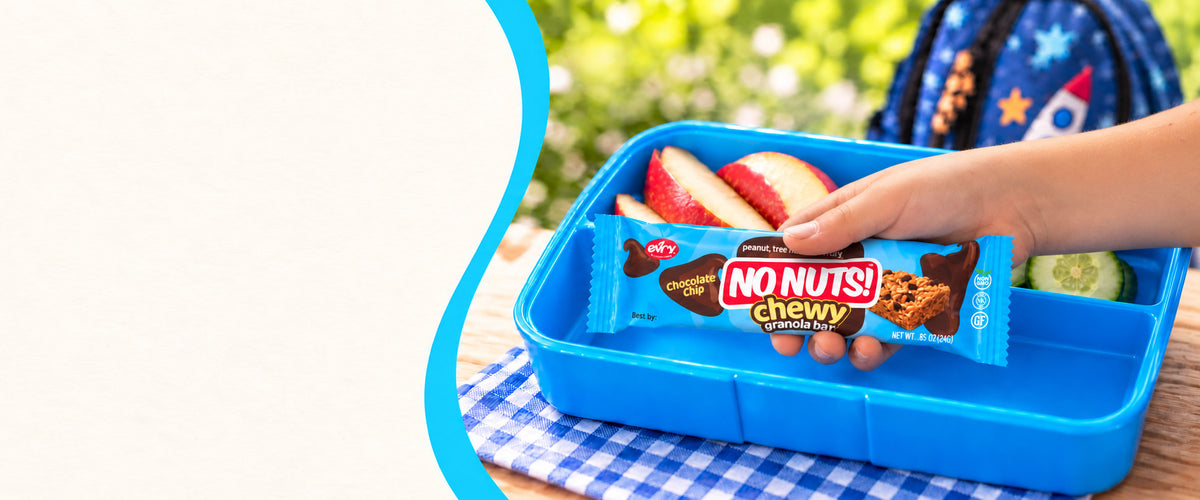 Child's hand picking a No Nuts! chewy chocolate chip nut-free granola bar from a blue school lunchbox