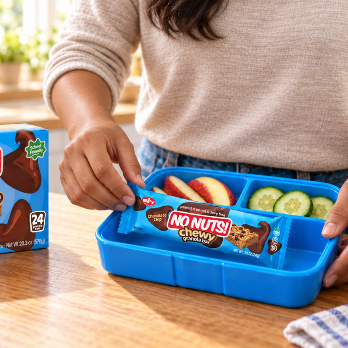 Parent packing a No Nuts! Chewy nut-free granola bar into a blue school lunchbox